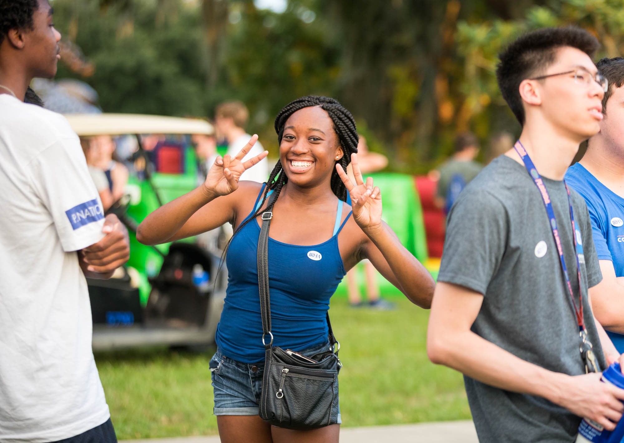 A student holds up two peace signs as they smile for the camera.