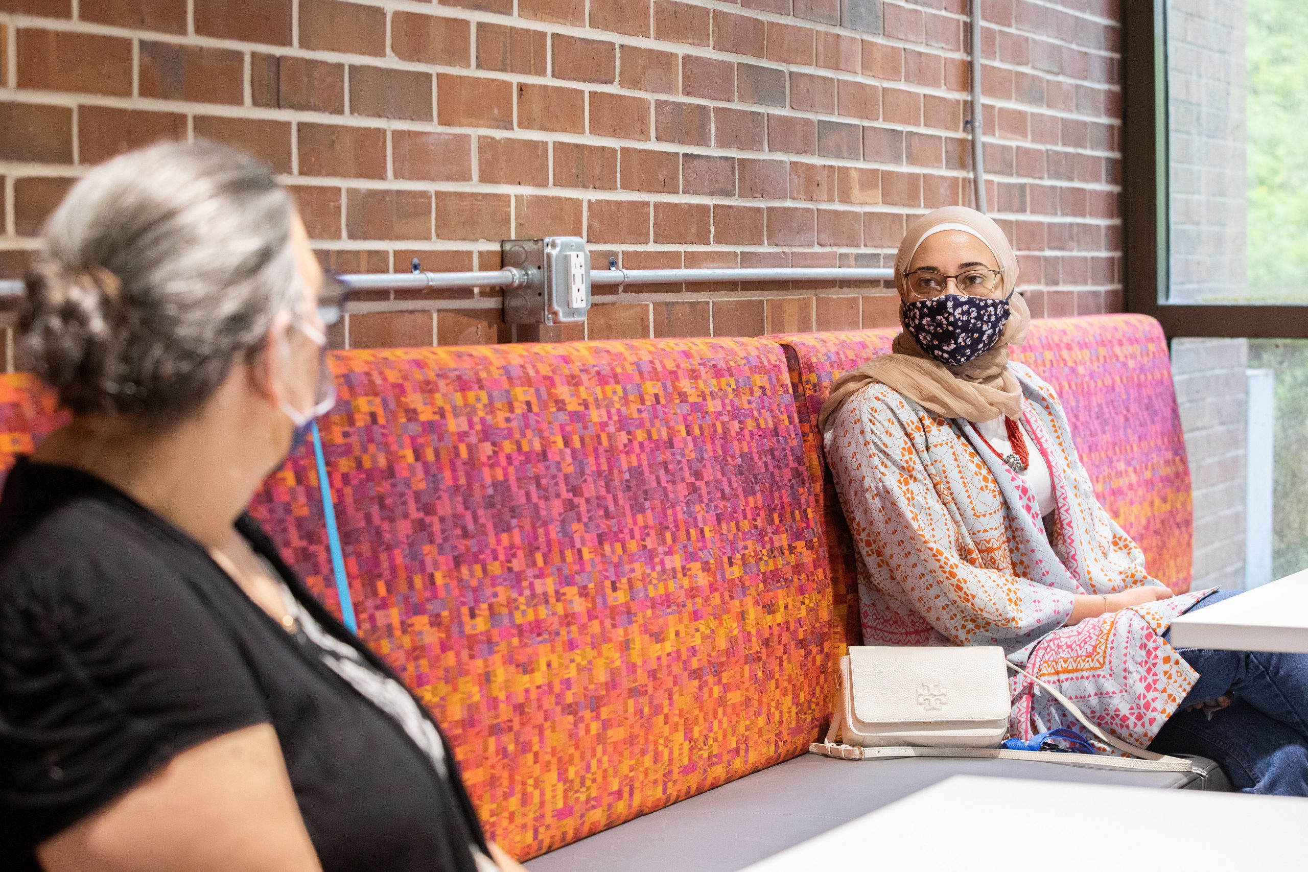 two students talk while wearing masks and socially distancing.