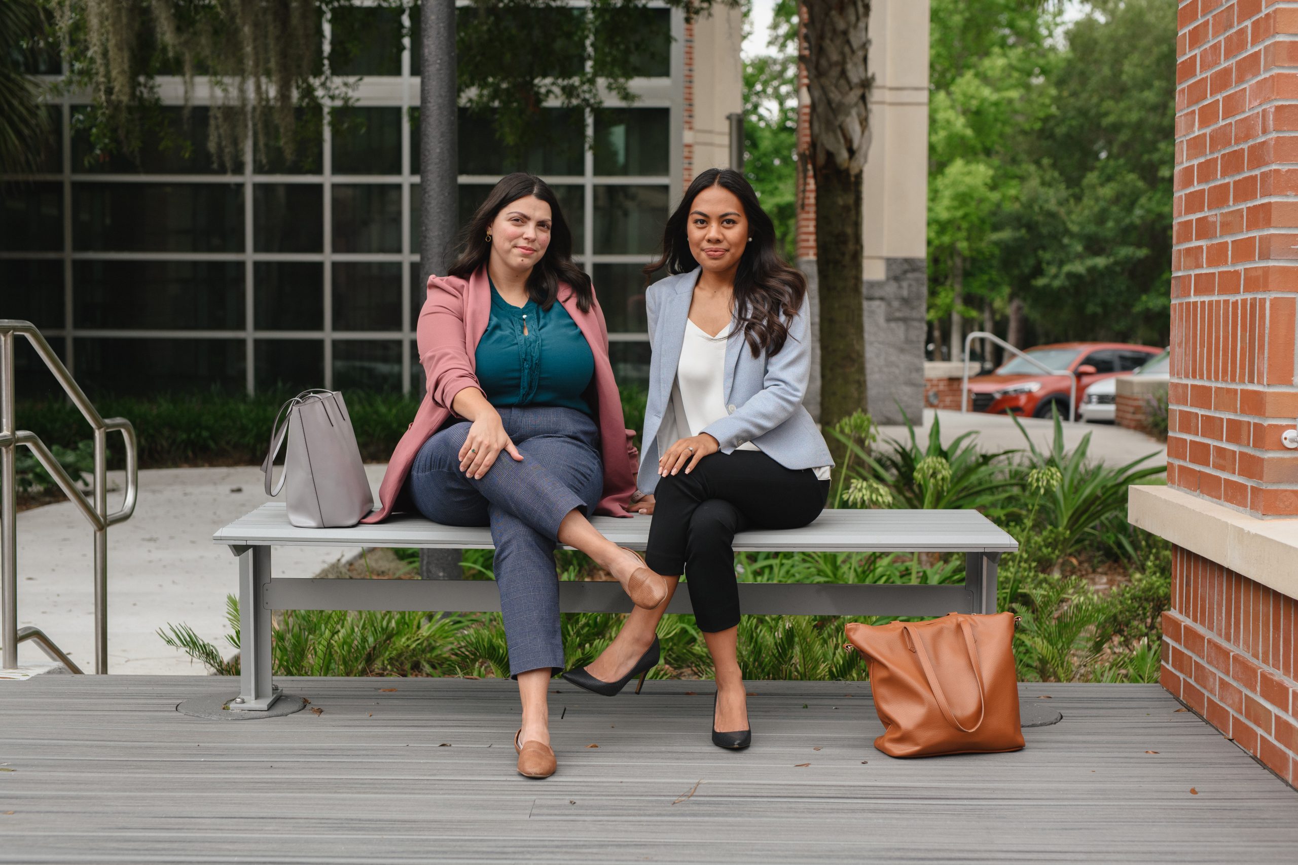 Two women in blazers sit outside the college of law.