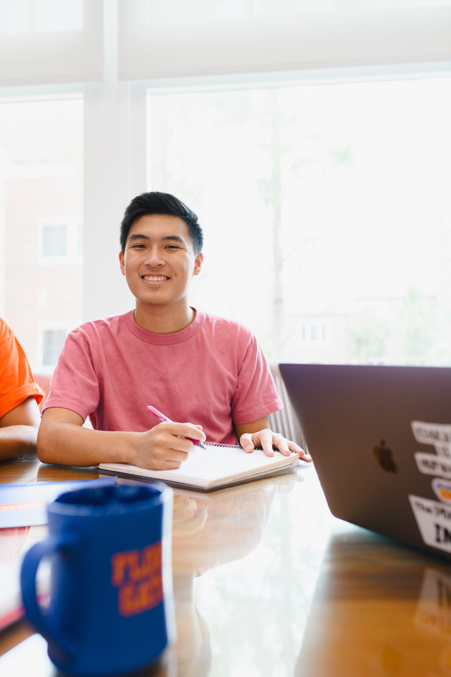 A male student smiles while working in Newell Hall with his classmates.