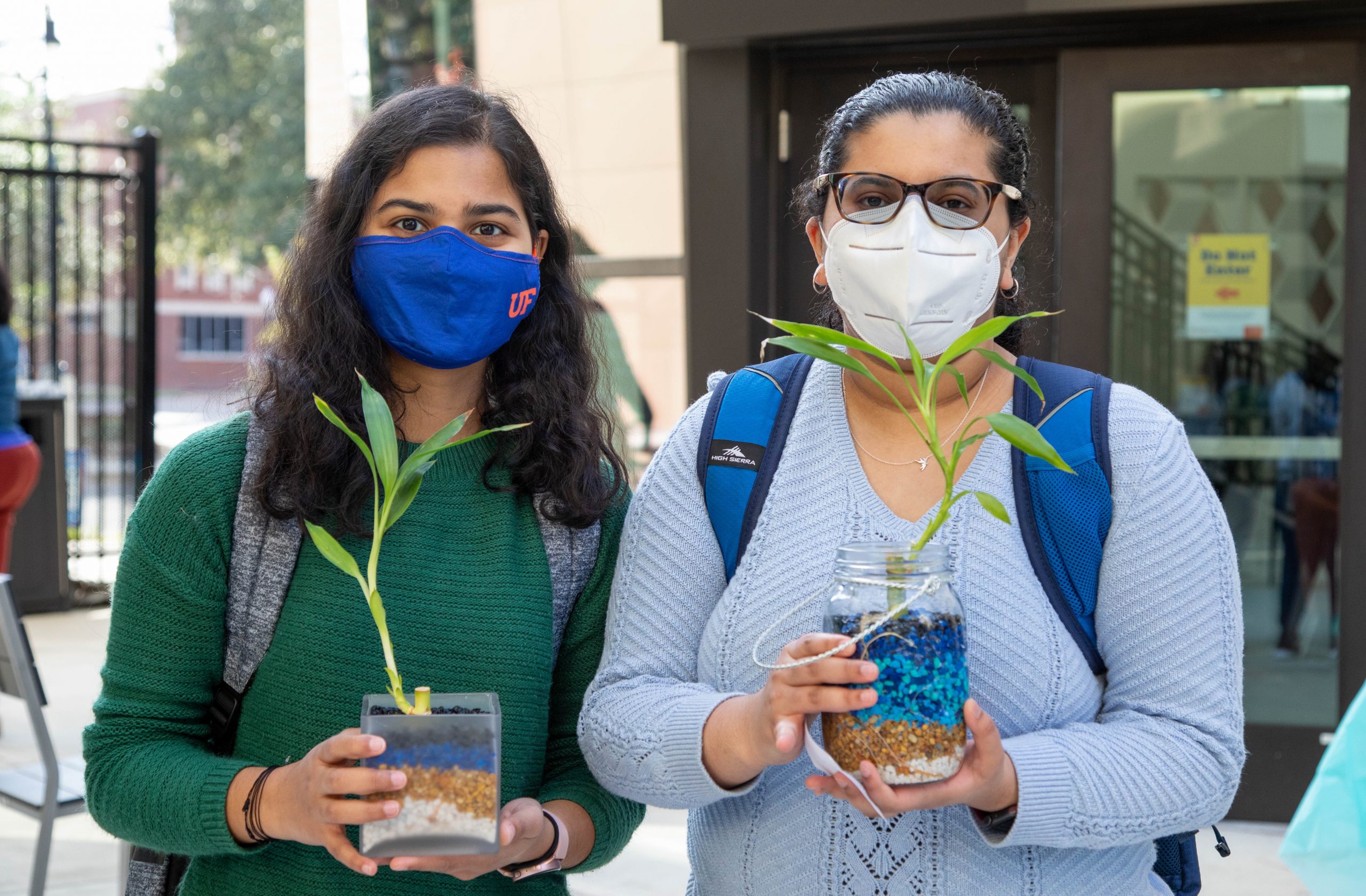 Two female students hold plants.