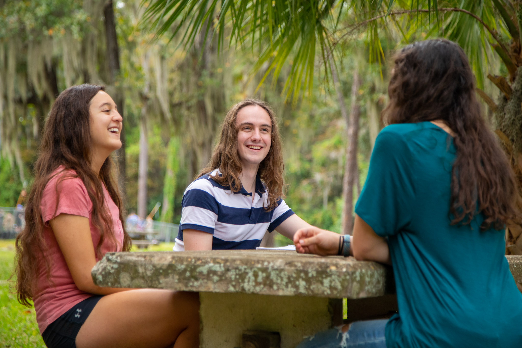 Three students chat outside on the lawn of Hume Hall.