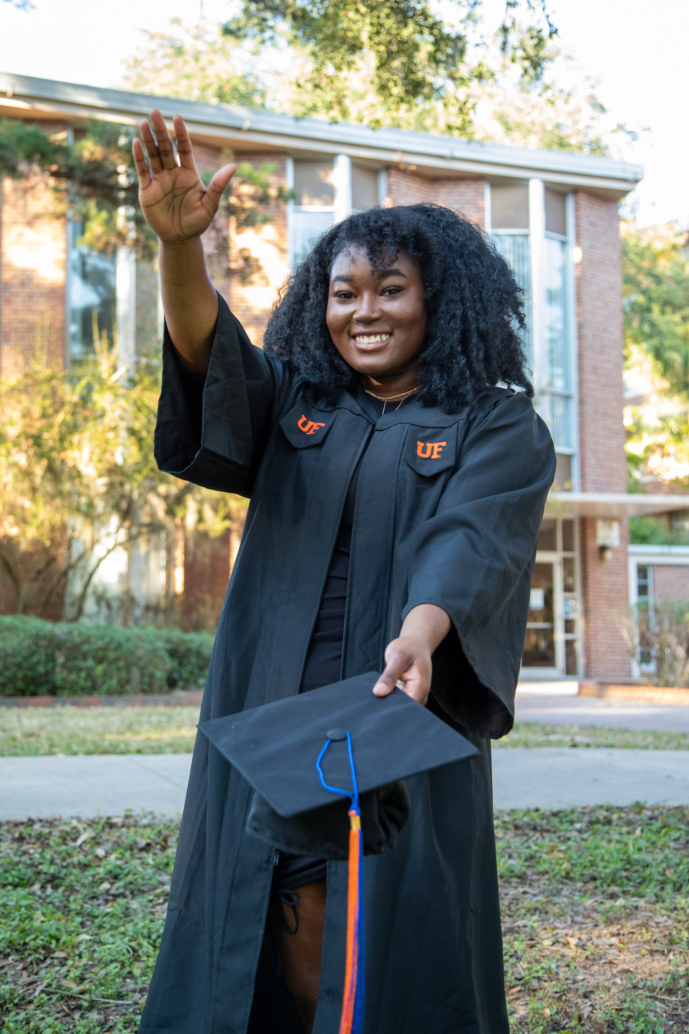 A student dressed in a graduation gown does a gator chomp.