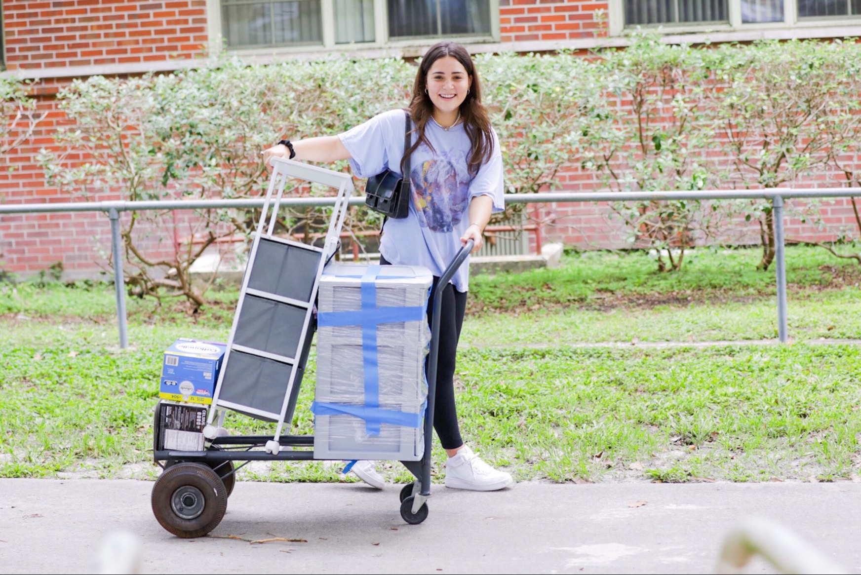 A female student moves her belongings in on a cart.