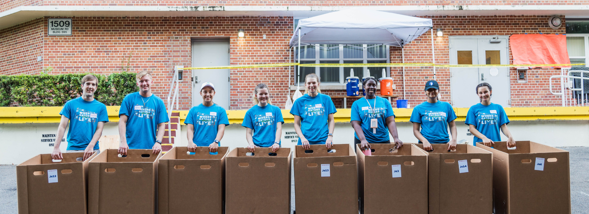 Eight volunteers stand ready to with cart to unload student vehicles for incoming students.