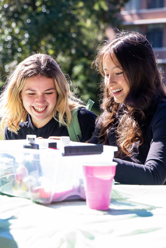 Two students laugh at the make crafts outside of weaver hall.