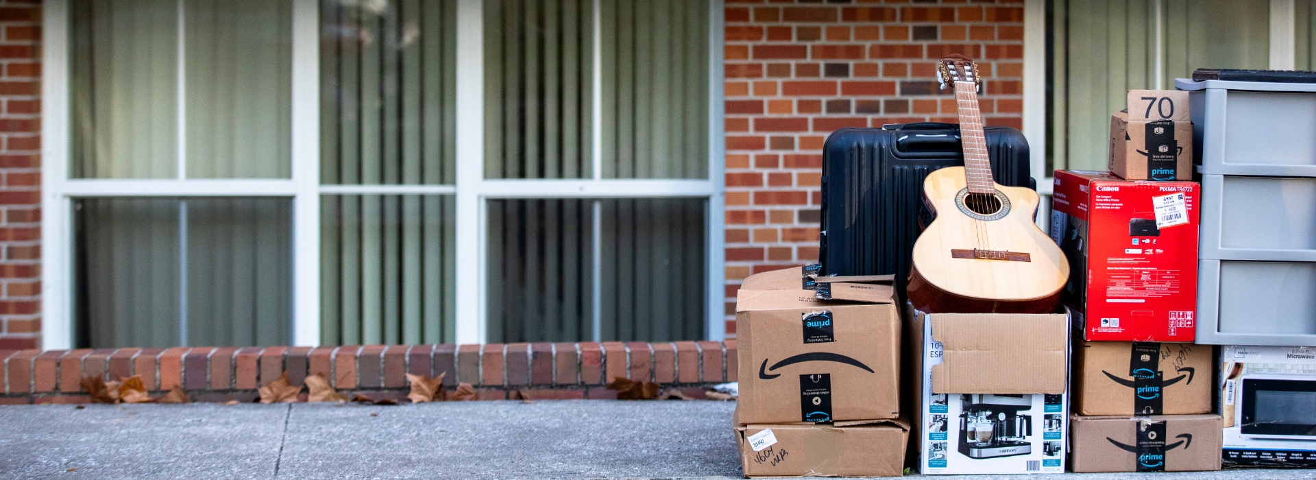 boxes and a guitar sit outside of a hall on the side walk as a student moves in.